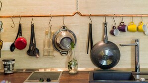 A kitchen with hanging utensils, a coffee maker, a kettle, and a frying pan. - Apartments Eos & Vespera (Dubrovnik)