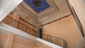 Un escalier orné de rampes en métal ouvragé et un plafond décoré de motifs.
