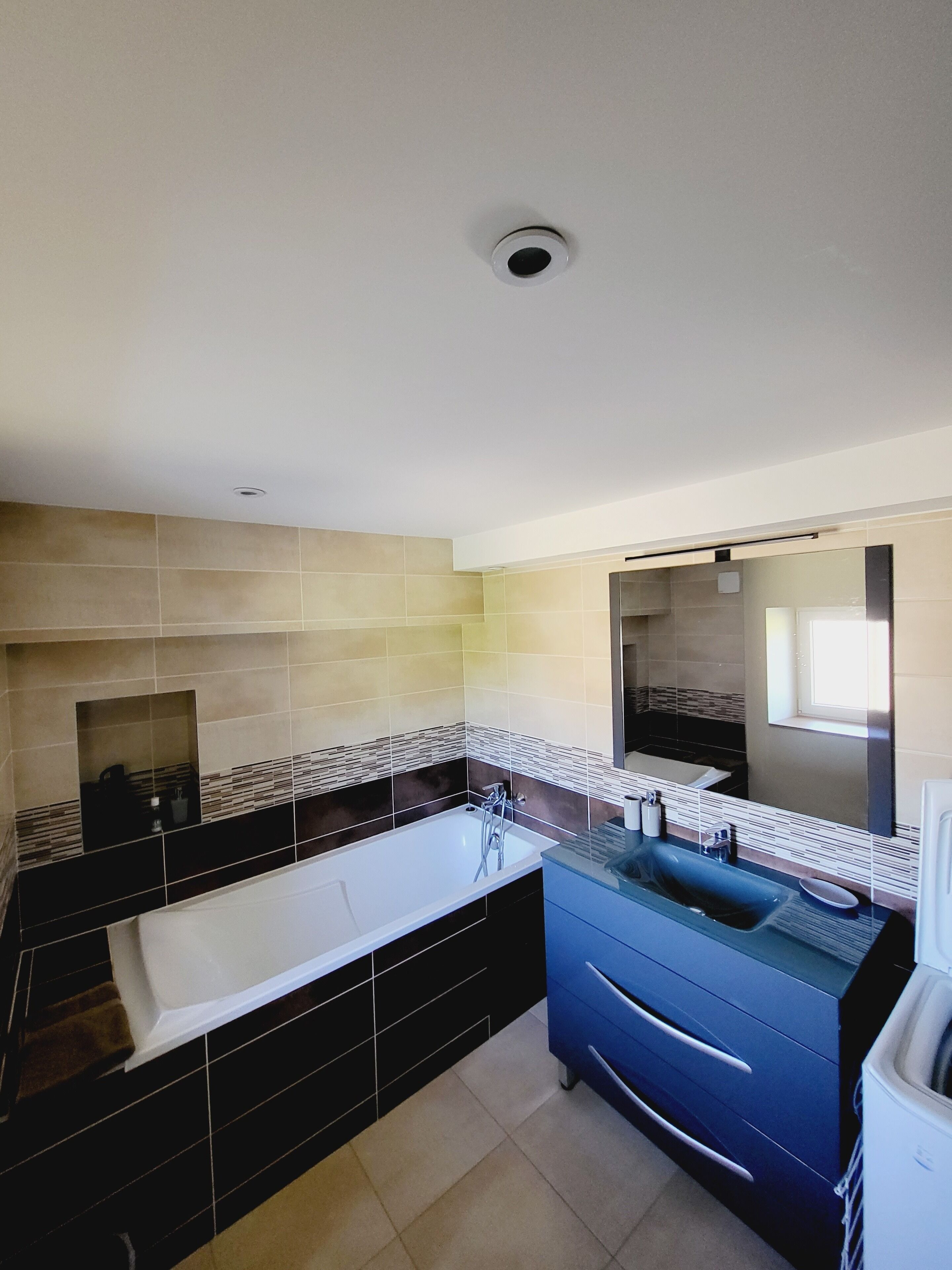 Une salle de bain moderne avec une grande baignoire, un lavabo doté d’un plan de travail bleu et un miroir au-dessus du lavabo.