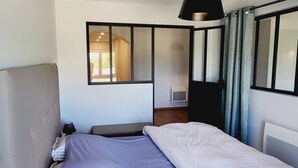 Une chambre à coucher moderne avec un grand lit, une table de chevet, une lampe et une fenêtre avec des rideaux.