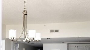 Eine moderne Küche mit weißen Schränken, einem Edelstahl-Kühlschrank und einem Essbereich mit weißem Tisch und Stühlen.