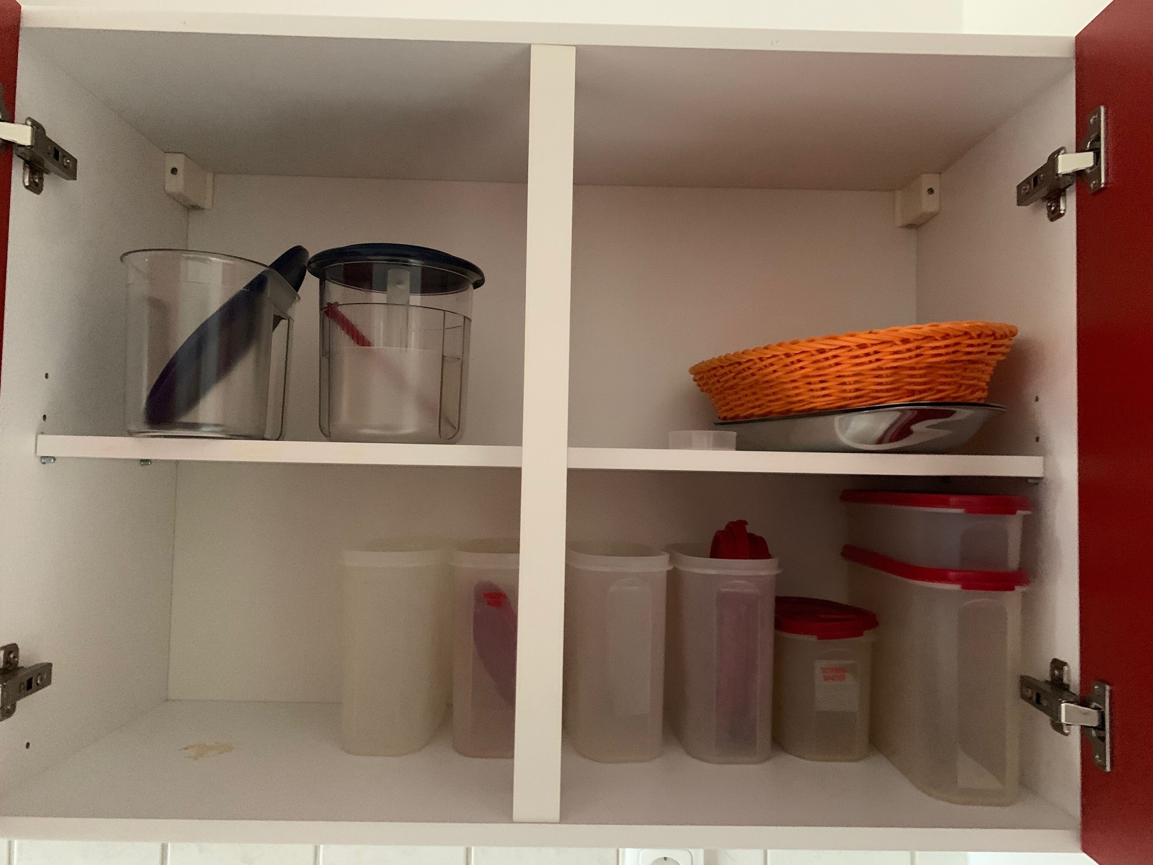 A white cabinet with four shelves, containing various storage containers and a basket.