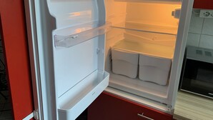 Un refrigerador abierto con estantes transparentes y un compartimento congelador.