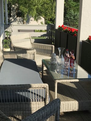 An outdoor patio with wicker furniture, a glass table, and decorative items.