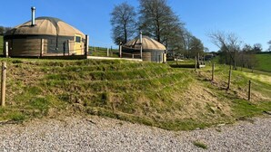 Two yurts on a grassy hill with a clear sky. - Looe Yurts (Looe)