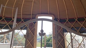 A circular ceiling with a skylight, wooden beams, and a central support structure. - Looe Yurts (Looe)