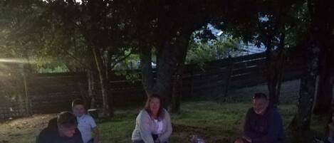 A group of people gathered around a campfire in a wooded area.