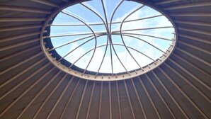 A bed in a yurt with a circular skylight above. - Looe Yurts (Looe)