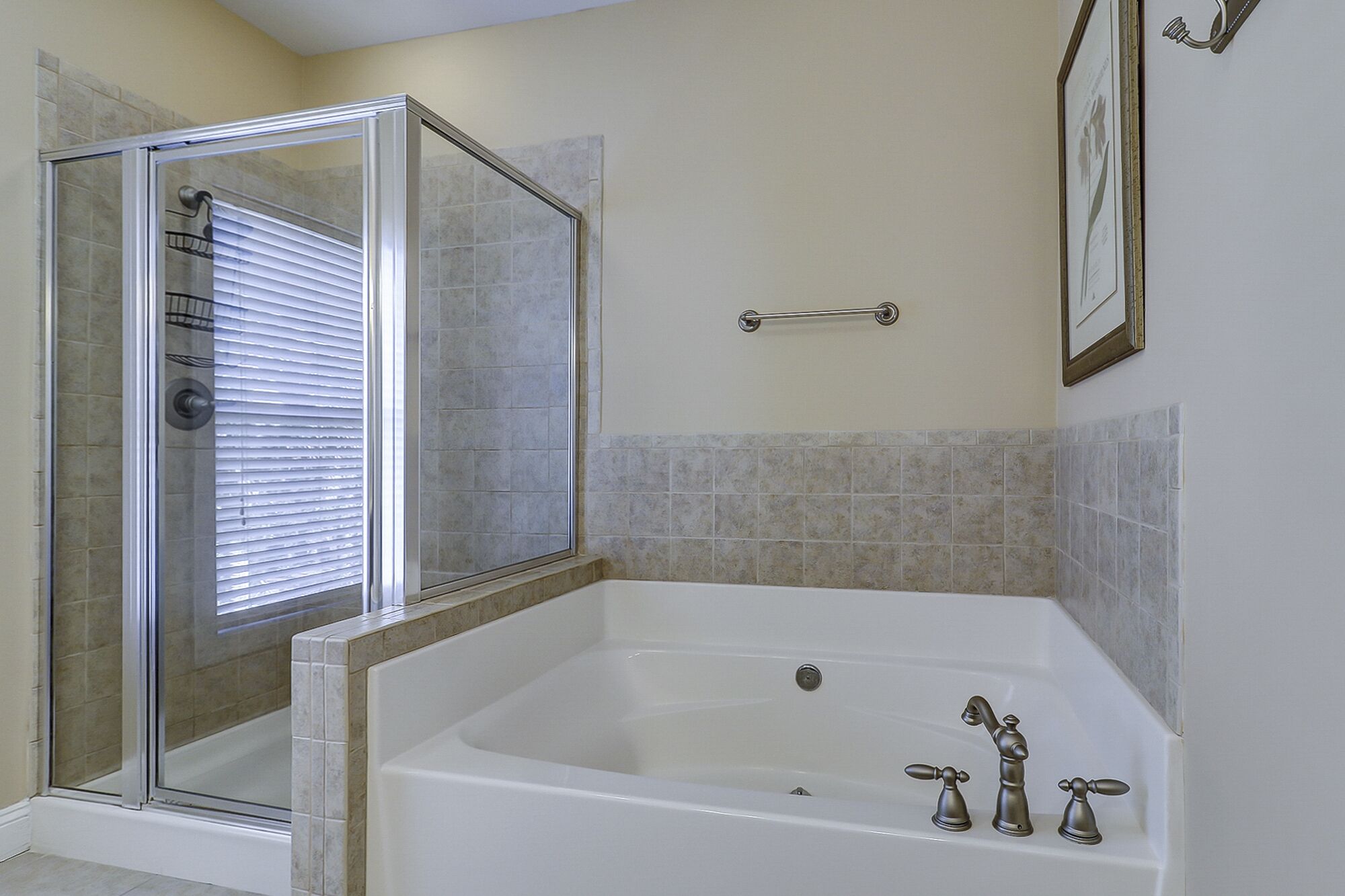 Une salle de bain avec une douche à parois de verre, une baignoire blanche dotée de trois robinets et des murs carrelés.