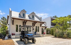 A modern house with a covered porch, a golf cart, and a well-maintained garden. - Private Pool, LSV, Pet Friendly & Beach Access (Santa Rosa Beach)