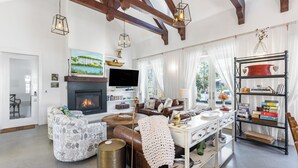 Una sala de estar con chimenea, sofá, mesa de centro y estantería.