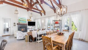 Amplia sala de estar con chimenea, una mesa de comedor con sillas y un televisor montado en la pared.