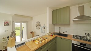 A kitchen with a wooden countertop, a sink, a stove, and green cabinets. - Petronella - Gardagate (Soiano)