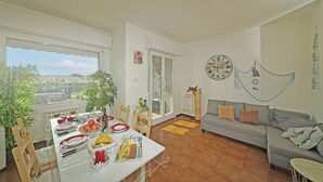 A dining area with a table set for a meal, a sofa, and a wall clock. - Petronella - Gardagate (Soiano)
