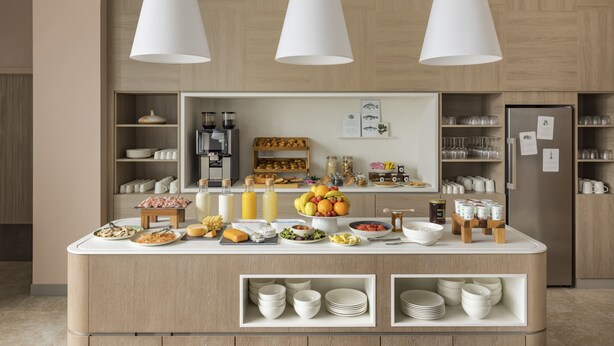 A modern kitchen with a breakfast bar, wooden cabinets, and a refrigerator. - OKKO Hotels Lille Centre (Lille)