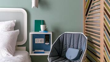 A bedroom with a bed, a chair, a nightstand, and a wall-mounted light.