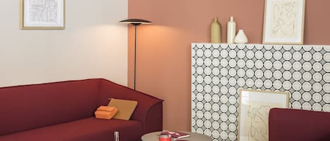 Una sala de estar moderna con un sofá rojo, un cojín amarillo, una mesa de centro redonda y un papel tapiz estampado.