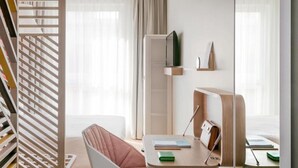A modern, minimalist room with a wooden slatted partition, a cushioned chair, a desk with a lamp, and a large mirror reflecting the room. - OKKO Hotels Lille Centre (Lille)