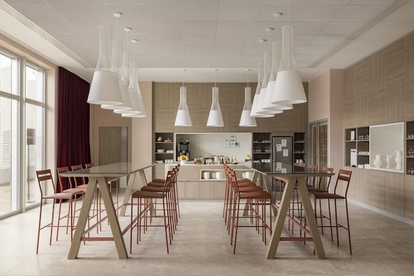 Una cocina moderna con una larga mesa de comedor y sillas, luces colgantes y vistas de la ciudad a través de amplios ventanales.
