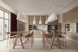Cozinha moderna com uma mesa de jantar comprida e cadeiras, luminárias pendentes e vista para a cidade através de janelas amplas.