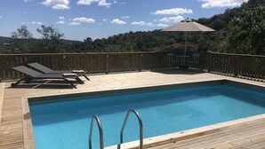 Ein rechteckiger Pool mit Metallleitern, umgeben von einer Holzterrasse.
