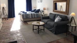 Ein modernes Schlafzimmer mit einem Bett, einer Couch, einem kleinen runden Tisch und einem Spiegel.