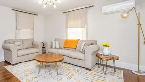 Un salon avec un canapé beige, une table basse en bois et un lampadaire.