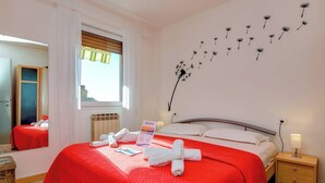 Ein Hotelzimmer mit einem großen Bett, einem Nachttisch, einem Fenster mit Vorhängen und einer Wanddekoration mit Löwenzahn.