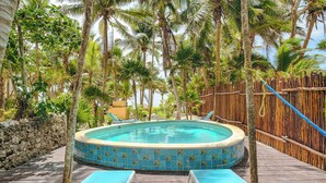 A circular pool with a tiled edge, surrounded by a wooden deck and a bamboo fence.