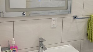 Ein Badezimmer mit einem weißen Waschbecken, einem Spiegel und einem grünen Handtuch.