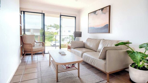 A modern living room with a sofa, a chair, a coffee table, and a potted plant.