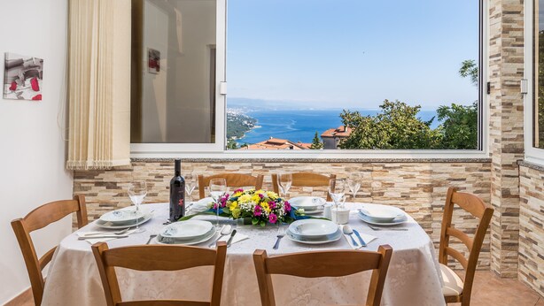 Une table à manger dressée pour six personnes, avec vue sur la mer.