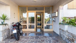 Une moto était garée devant un bâtiment dont l’entrée était recouverte de pierres et qui possédait une porte en verre donnant sur l’intérieur.