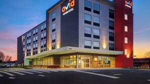A modern hotel with a prominent 'avid' sign, a glass entrance, and a red accent wall. - avid Hotel Fort Mill - Carowinds Blvd by IHG (Fort Mill)