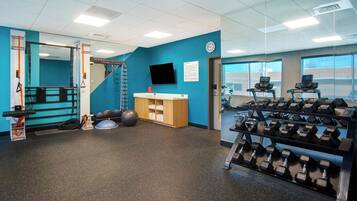 A gym with exercise equipment, a wall-mounted TV, and a window with a view.