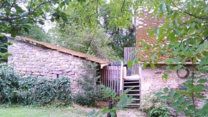 Ein rustikales Steinhaus mit einer Holztreppe, die zu einer Holzdiele führt.
