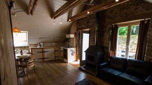 Ein gemütliches Blockhausschlafzimmer mit einem Holzesstzimmer, einer Couch, einem Kamin und einer Küchenzeile.