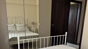 Une chambre à coucher comprenant un lit, une armoire, un ventilateur de plafond et une table de chevet.