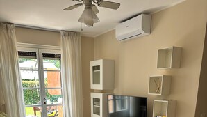Un salon moderne doté d’un téléviseur à écran plat, d’un canapé, d’une table à manger et d’un ventilateur de plafond.