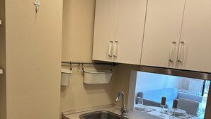 Une cuisine de taille réduite, équipée d’un évier, de placards et d’un plan de travail.