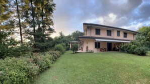 Une maison à deux étages dotée d’un patio couvert et d’une pelouse bien entretenue.