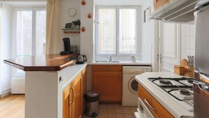 A compact kitchen with a stove, sink, and washing machine. - Beautiful flat in Montparnasse (Paris)