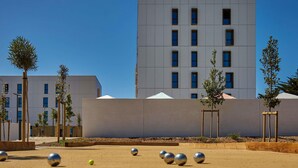 Une cour intérieure avec un bâtiment moderne, quelques arbres et une rangée de sphères métalliques.