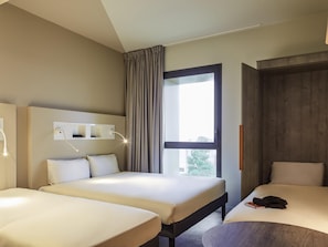 Una habitación de hotel con dos camas, un ventanal grande, un espejo y una mesita de noche.