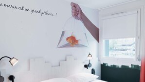 A bedroom with a bed, a nightstand, a wall-mounted lamp, and a window. - ibis Styles Thonon Les Bains Hotel (Thonon-les-Bains)