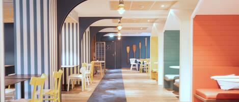 A modern interior with a central hallway, striped walls, and a variety of seating arrangements including tables and chairs.