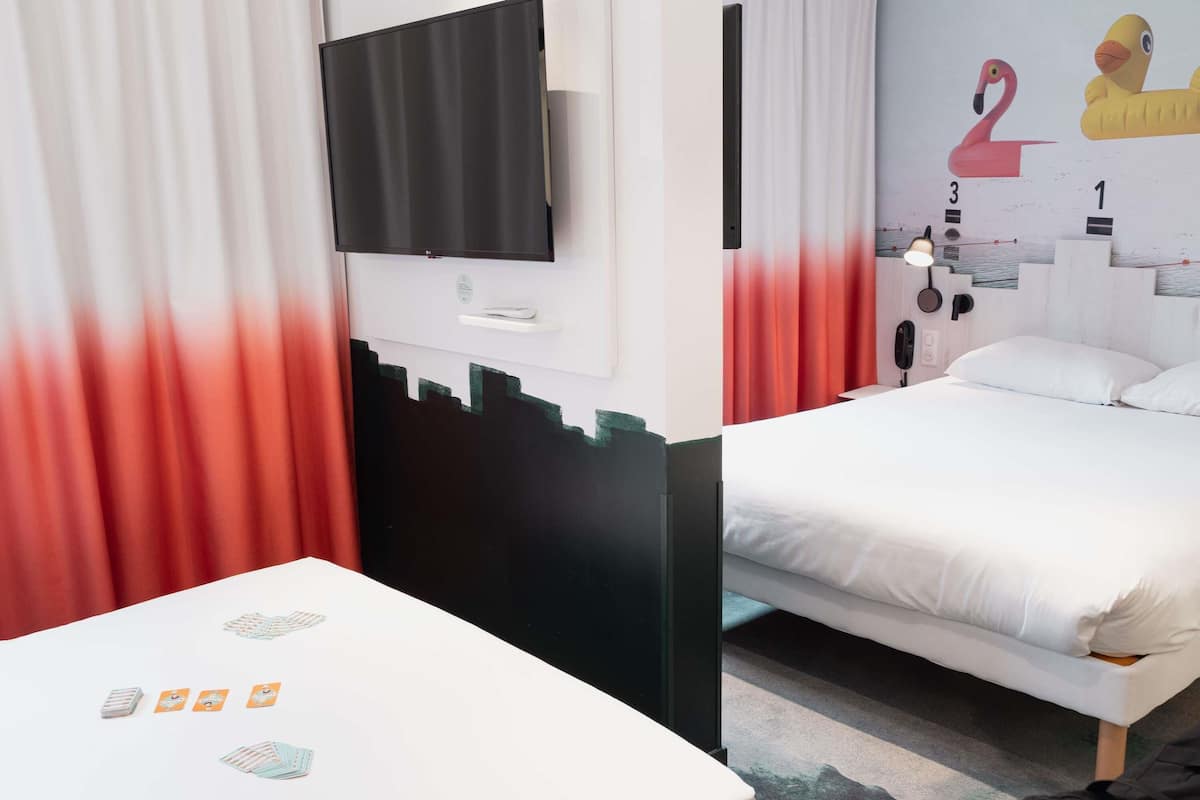 Quarto de hotel com uma cama, uma televisão fixada na parede e uma decoração na parede.