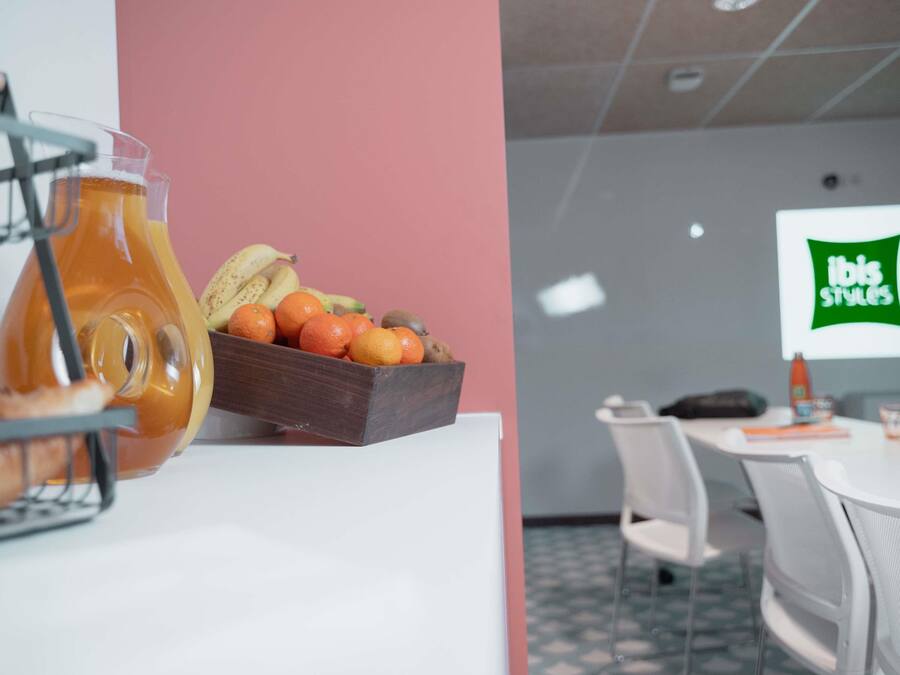 En frukostuppsättning med en fruktskål och en kanna apelsinjuice på ett vitt bord.
