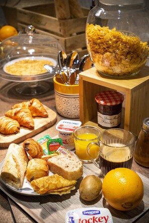 Ett frukostbord med croissanter, bröd, apelsinjuice och en skål med flingor.
