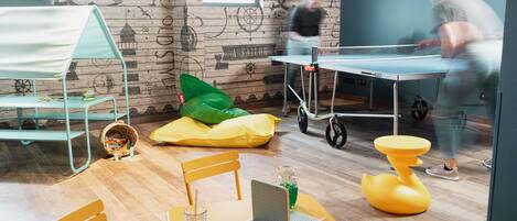 Une pièce avec un mur en bois, une table avec un ordinateur portable, des chaises et une table de ping-pong.